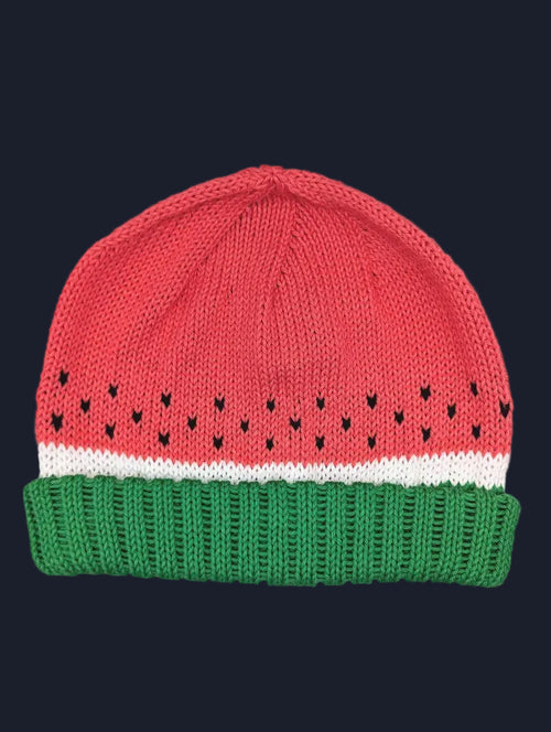 A knitted beanie hat designed to look like a watermelon slice, featuring a red top section with small black seed details, a white stripe, and a green ribbed bottom band.